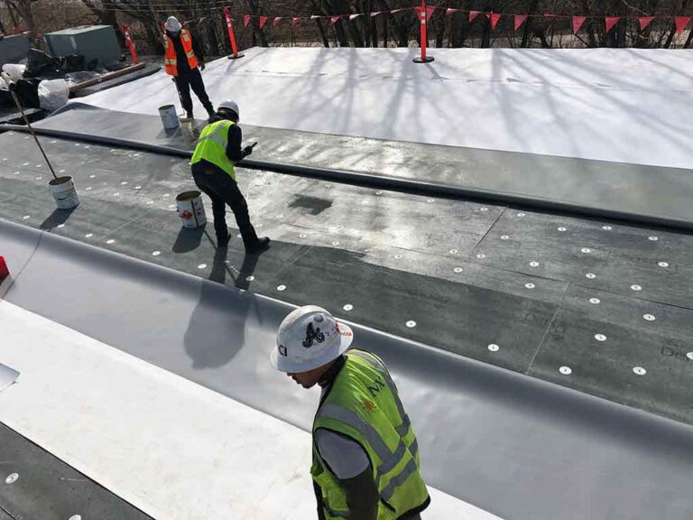 Crew installing fully adhered TPO roof